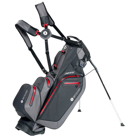 A black and gray golf bag with red accents stands upright on two legs displaying multiple pockets for storage and equipped with shoulder straps for easy carrying.