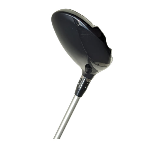 A black golf driver rests upright showcasing its large, rounded clubhead and a metallic shaft. The adjustment markings for loft settings are visible on the club's neck.