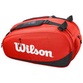 A red sports bag is displayed with a large white Wilson logo prominent on the side it has multiple compartments including a zippered opening and padded straps for carrying.