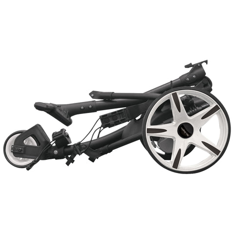 A folded stroller lies on its side showcasing its compact design with a black frame and distinctive white-spoked wheels in a minimalist setting emphasizing portability and storage convenience.