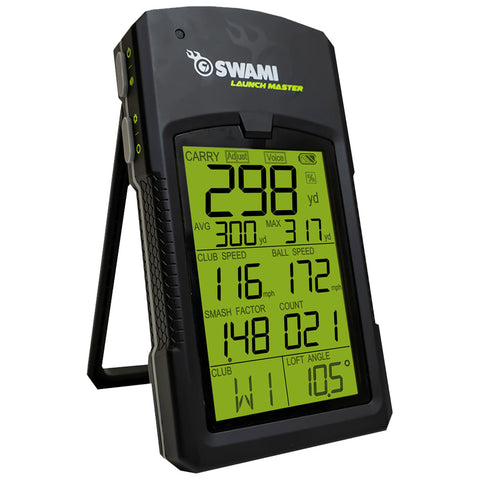 A black golf launch monitor displays numerical data on a bright green screen showing statistics like carry distance club speed and ball speed while standing on a small foldable tripod.