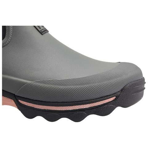 A gray rubber shoe with textured surface and a slightly curved toe section is positioned. It features a pinkish strip along its side, suggesting a modern design intended for outdoor use.