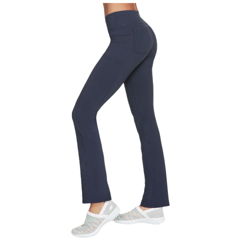 Navy blue flared leggings are being worn by a model who stands sideways displaying a fitted silhouette paired with light-colored slip-on shoes in a neutral setting.