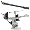 A golf club fitting tool is positioned on a flat surface with a black adjusting lever on top and a white base featuring adjustable clamps and guides for precise alignment of the club.