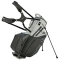 A golf bag stands upright with extended legs. It features adjustable straps and zippers, designed for carrying golf clubs. The bag has a sleek modern design in gray and black.