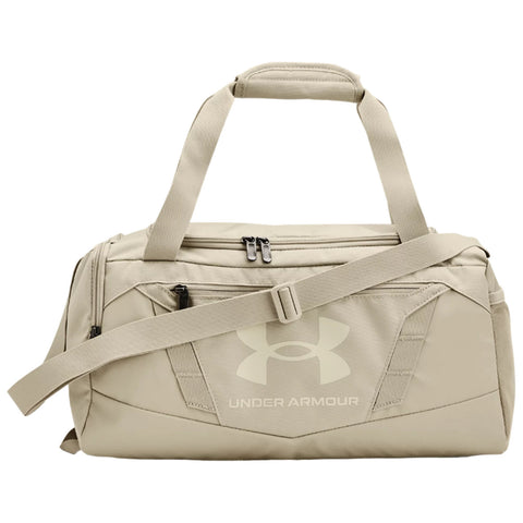 A beige duffel bag features dual handles and a detachable shoulder strap with zippers on top and a small front pocket showcasing the Under Armour logo prominently on the side.