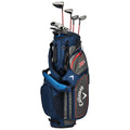 A navy golf bag stands upright with clubs inserted at the top featuring a shoulder strap and various pockets for accessories set against a neutral background.