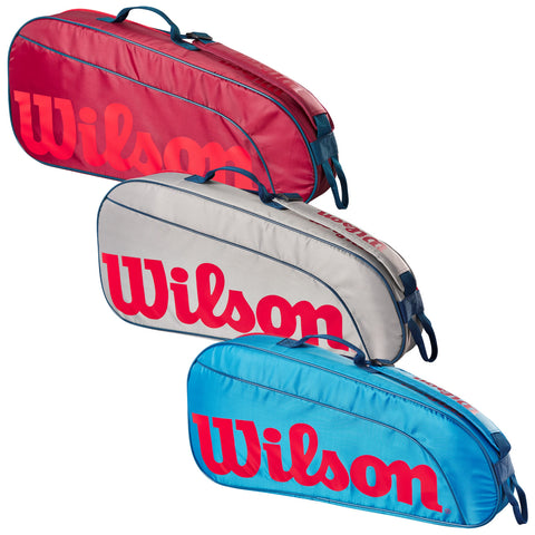 Three tennis bags in red gray and blue are displayed side by side with the word Wilson prominently featured on each bag highlighting their sporty design and function as equipment carriers.