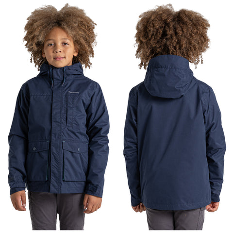 A child with curly hair is wearing a dark blue jacket with a hood and two front pockets while standing upright against a plain white background.