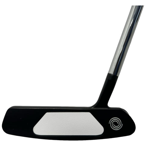 A golf putter is positioned vertically with its flat black face and white striking surface facing outward the shiny silver shaft extends upward from a black grip area