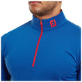 A blue athletic top with a red zipper and red logo is worn by an individual shown from the torso upward, highlighting the garment's sleek design and sporty style.