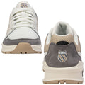 K-Swiss sneakers are shown from the front and back with a white mesh upper and grey suede accents. The context is a neutral background emphasizing the shoe's design features and logo.