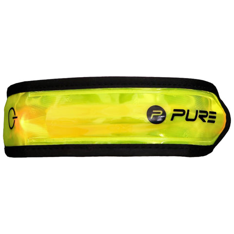 A yellow reflective armband is displayed resting flat showing light dispersion and branding the word PURE on one side while the opposing side has a circular symbol indicating functionality in low-light conditions.