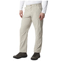 Light-colored hiking pants are worn by a person standing upright with one hand resting on the hip while wearing sturdy boots amidst a neutral background suggesting an outdoor environment.