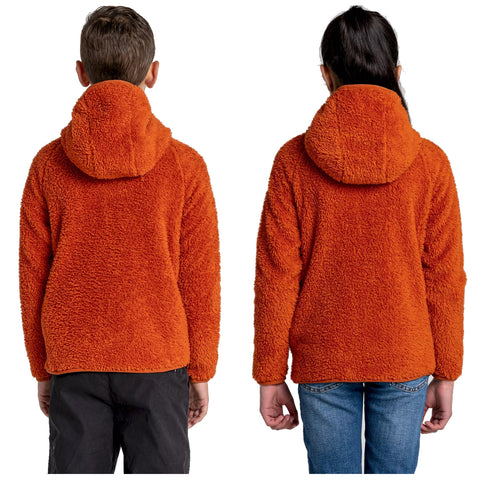 Two children are wearing soft orange hooded jackets standing back to back with one child in black pants and the other in blue jeans in a neutral background.