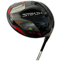 A black golf driver with red accents is angled slightly. It features a glossy surface and is labeled "STEALTH" and "PLUS+" indicating its brand and model within a neutral background.