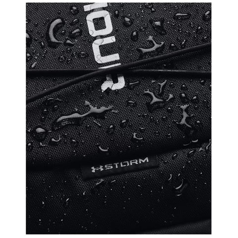 A black fabric bag is covered in water droplets showcasing its waterproof surface with a visible logo and the word STORM on a tag, indicating durability in wet conditions.