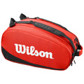 A red sports bag with black accents sits prominently with the word Wilson in large white letters on its side indicating it is designed for carrying sports equipment or gear.