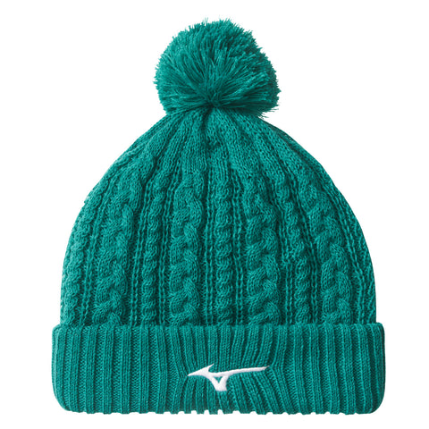 A teal knit beanie with a pom-pom on top is displayed upright showcasing textured cable stitching and a ribbed cuff featuring a white logo on the front.