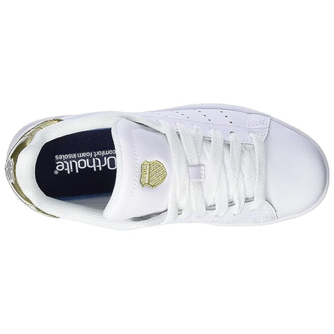 A white sneaker features gold accents and laces. The sneaker is positioned upright with a view of the top and interior lining, surrounded by a plain background.