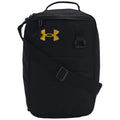 A black backpack with a gold Under Armour logo is displayed resting upright featuring a top handle and an adjustable shoulder strap suitable for carrying various items.