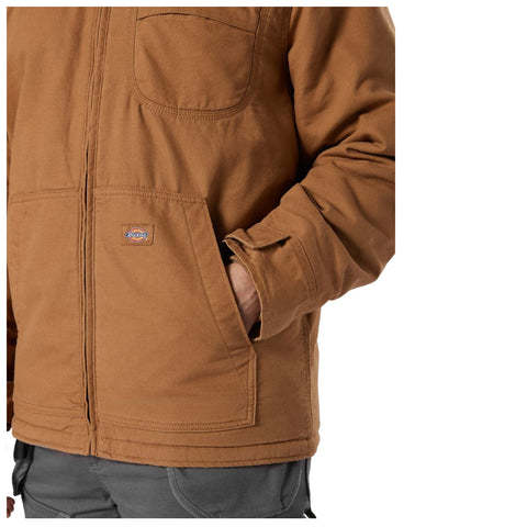 A brown jacket is partially visible with a hand placed in the pocket the jacket displays a logo and features a zip closure and a simple design suitable for casual wear.