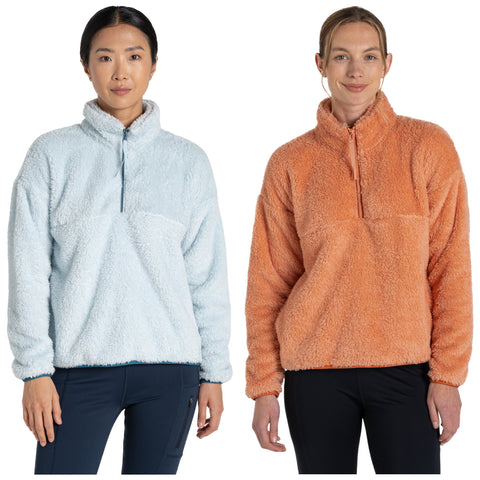 Two women stand side by side wearing fuzzy pullovers one light blue and the other orange both with half zippers they are posing against a plain white background