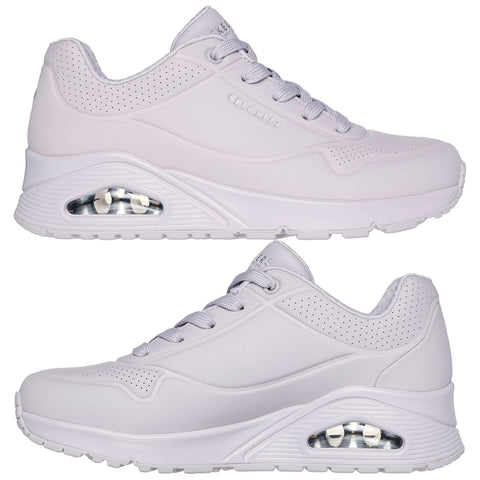 A pair of white athletic shoes with a sleek design features a visible air cushioning unit and is placed against a neutral background showcasing their smooth surface and textured accents.