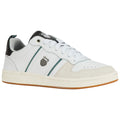 A white sneaker with green and black accents features stylish lines and a logo on the side while resting on a plain surface. The shoe has a classic athletic design.