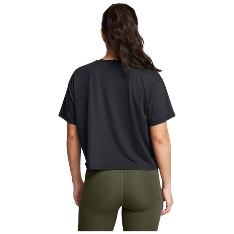 A person is facing away, wearing a black cropped t-shirt and olive green leggings, within a plain, neutral background suggesting an active or casual environment.