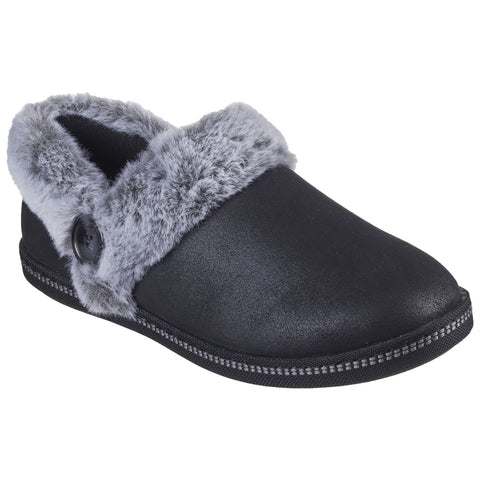 A black slipper with a gray faux fur collar sits alone showcasing a smooth exterior and a decorative button on its side designed for comfort and warmth in indoor settings.