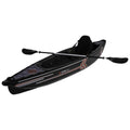 A black kayak with red and white accents is positioned at an angle showing its design it features a seating area and two paddles resting alongside ready for use