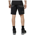 Black cargo shorts are being worn by a person standing with their back facing the viewer showing pockets and contrasting fabric panels with black athletic shoes and crew-length socks visible.