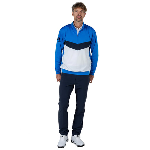 A male model stands upright wearing a blue and white pullover with dark pants and white shoes in a neutral background, showcasing a sporty and casual outfit.