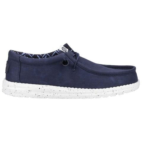 A navy slip-on shoe features a canvas upper and a white speckled sole, designed for casual wear with a relaxed aesthetic, suitable for indoor or outdoor use.