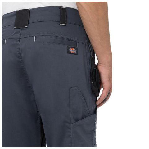 A person is wearing dark cargo pants with pockets and a tool belt attachment the fabric appears durable set against a neutral background highlighting the clothing's details