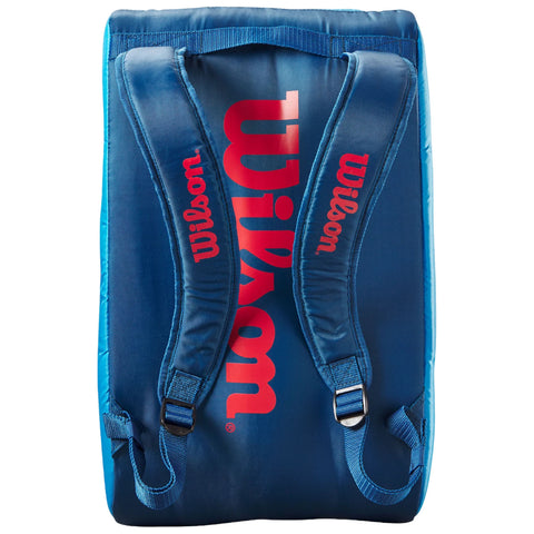 A blue backpack with red "Wilson" branding sits upright showcasing padded straps for carrying in a sports or school context designed for comfort and functionality.