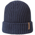 A navy blue knitted beanie sits upright displaying a ribbed texture with a folded cuff and a small leather tag on the side indicating brand identity in a simple and minimalist style.