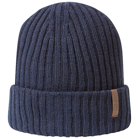 A navy blue knitted beanie sits upright displaying a ribbed texture with a folded cuff and a small leather tag on the side indicating brand identity in a simple and minimalist style.