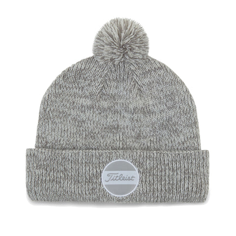 A gray knit beanie with a pom-pom on top is displayed flat its folded brim features a round logo patch labeled Titleist surrounded by a smooth background.