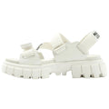 A white sandal with a chunky sole features adjustable straps. It is designed for comfort and style, suitable for casual outdoor activities.