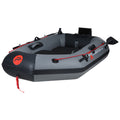 An inflatable boat sits on a flat surface featuring a grey exterior with black accents two seats inside and red rope detailing around the perimeter for securing gear.