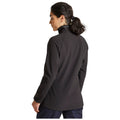 A person wearing a black pullover jacket stands with their back towards the viewer, appearing to look to the side, in a neutral background setting.