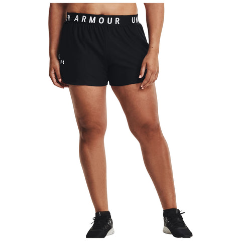 Black athletic shorts with a branded waistband are worn by an individual standing confidently in a neutral background, showcasing a sporty look suitable for exercise or casual wear.