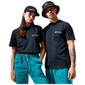 A young man and woman stand closely together wearing matching black t-shirts with a logo and bright turquoise pants with the man in a bucket hat and the woman in a cap.