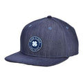 A blue denim cap features a circular patch with a four-leaf clover design and the text "BLACK CLOVER" and "LIVE LUCKY" showcasing a casual and stylish accessory suitable for outdoor wear.