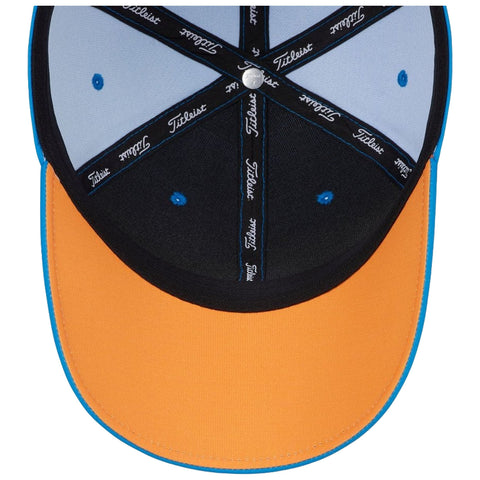 A colorful baseball cap is displayed upside down showing an orange brim and black and blue panels with a logo on the top inner lining surrounded by contrasting stitching patterns.