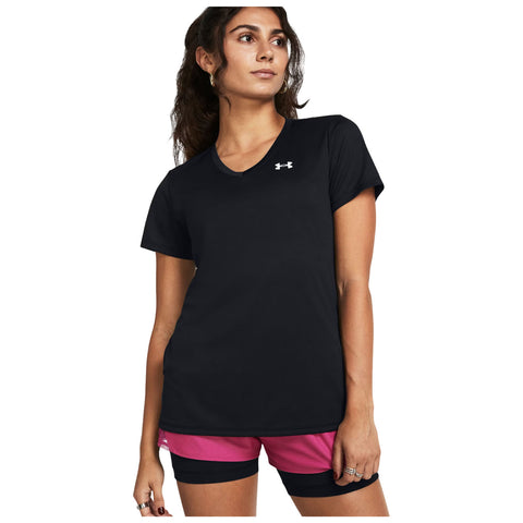 A person is wearing a black athletic shirt and pink shorts standing with a confident expression against a plain background showcasing the athletic attire.