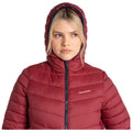 A woman poses wearing a zipped maroon puffer jacket with a hood. The background is plain white, highlighting her serene expression and the jacket's texture.