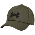 A green cap with a black Under Armour logo rests at an angle showcasing its curved brim and structured design against a neutral background.